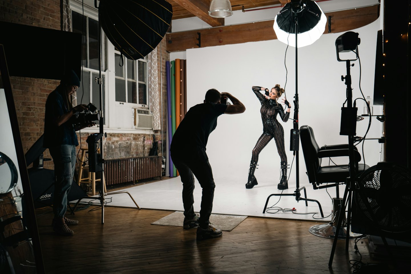 Un fotografo dirige una modella che posa in uno studio.