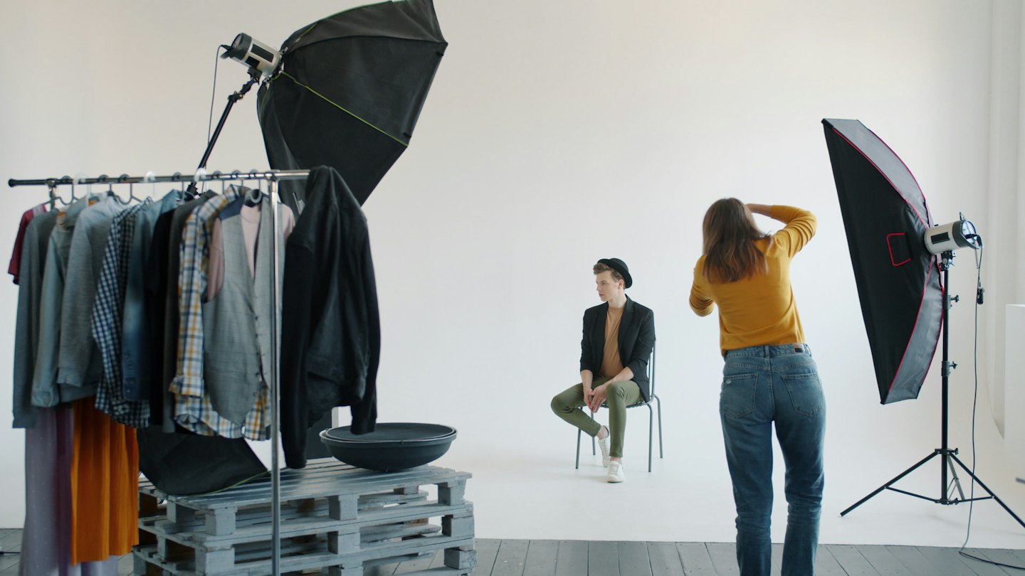 Un fotografo dirige un modello maschile in uno studio minimalista.