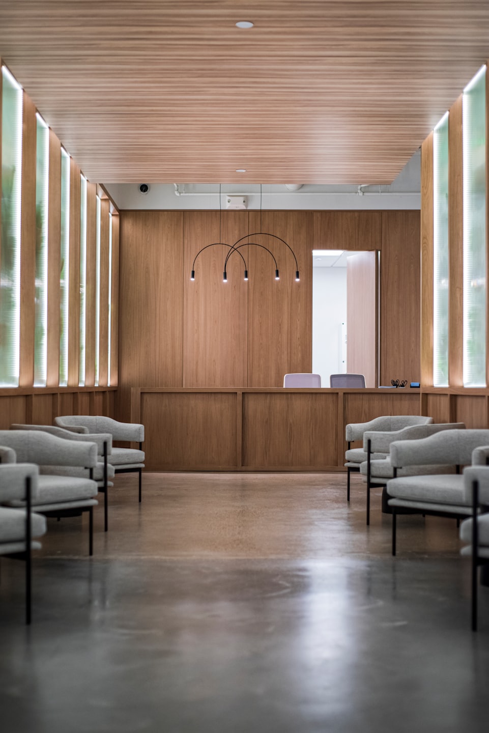 Sala d'attesa vuota con poltrone grigie e bancone della reception.